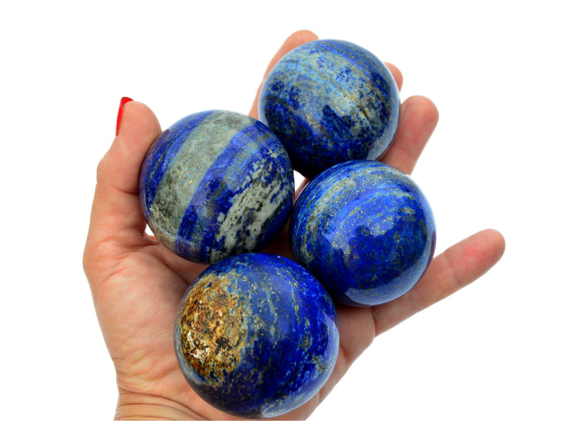 Four blue lapis lazuli sphere crystals 50mm on hand with white background