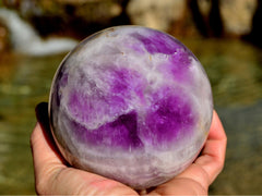 Extra large amethyst crystal sphere 95mm on hand with backround with river landscape