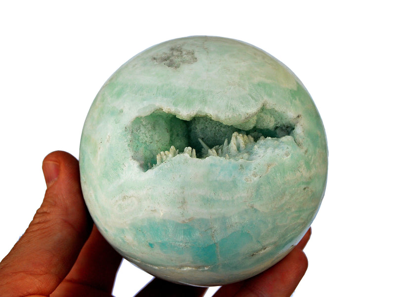 One large druzy caribbean blue calcite sphere 85mm on hand with white background