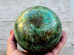 Extra large chrysocolla sphere 100mm on hand with wood background