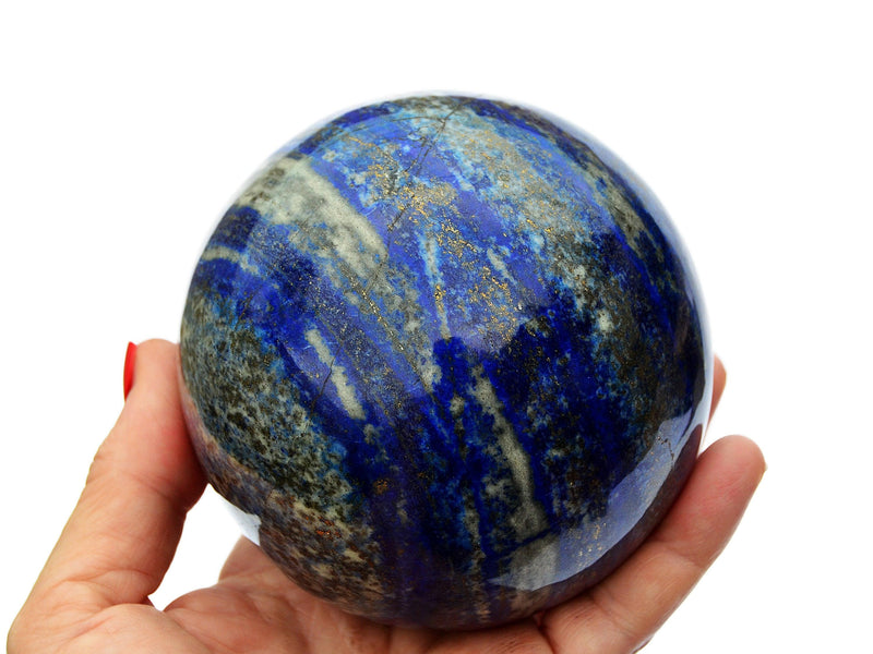 Large lapis lazuli crystal sphere 95mm on hand with white background