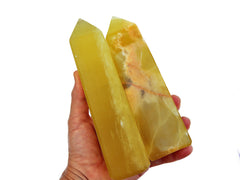 Two large lemon calcite towers 200mm on hand with white background