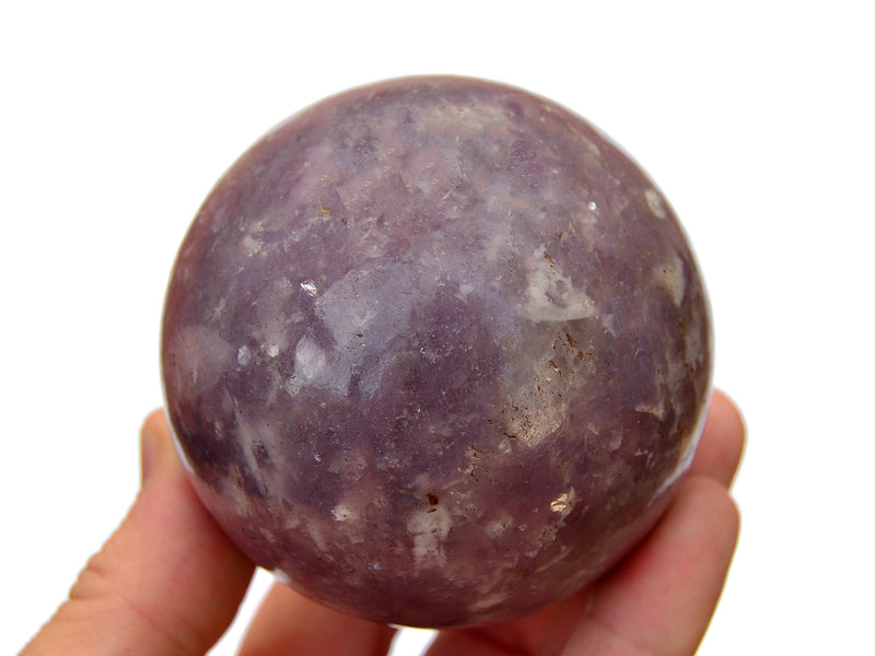 Large lepidolite crystal sphere 90mm on hand with white background