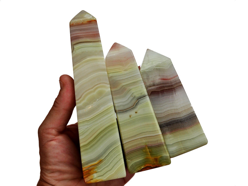 Three large pink banded onyx obelisks crystals on hand with white background