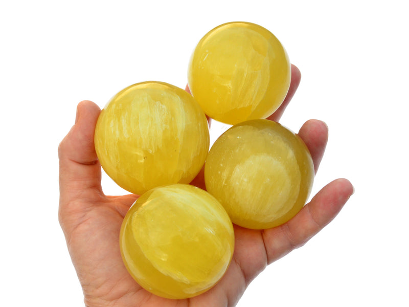 Four lemon calcite sphere crystals 55mm on hand with white background