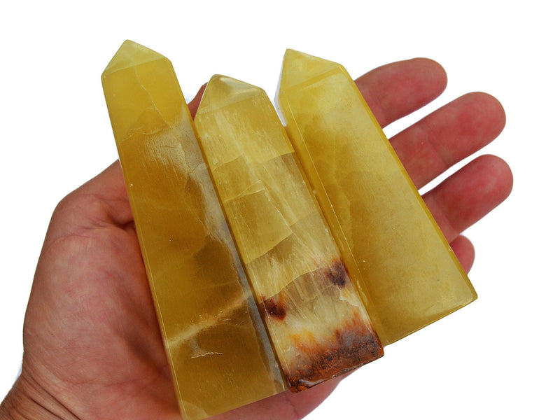 Three lemon calcite crystal obelisk 80mm-90mm on hand with white background