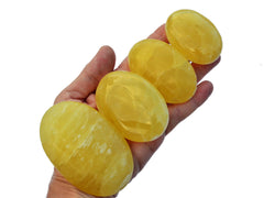 Four lemon calcite palm stones 40mm-85mm on hand with white background