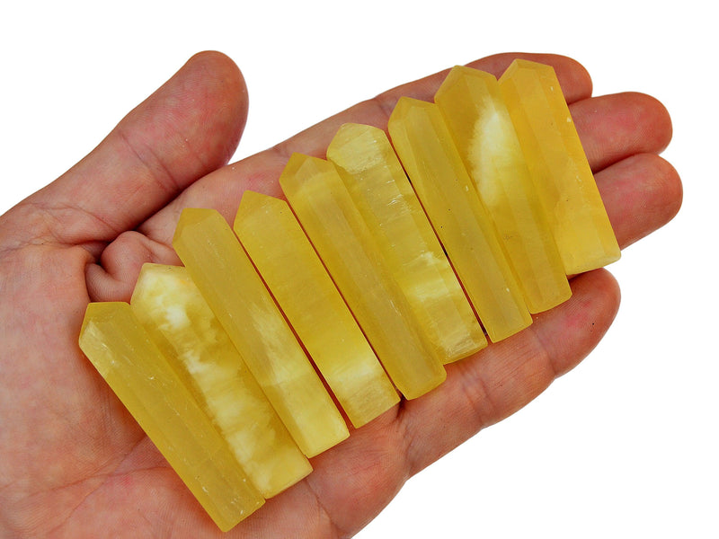 Nine lemon calcite mini tower crystals 50mm-60mm on hand with white background