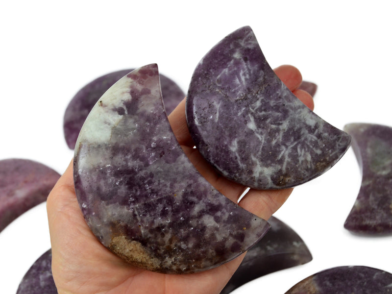 Two purple lepidolite shapped moon crystals 85mm-90mm on hand with background with some crystals on white