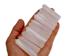 Ten pink mangano calcite faceted crystal points 55mm on hand with white background