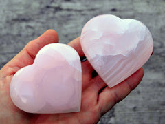 Two large mangano calcite pink hearts 65mm on hand with wood background
