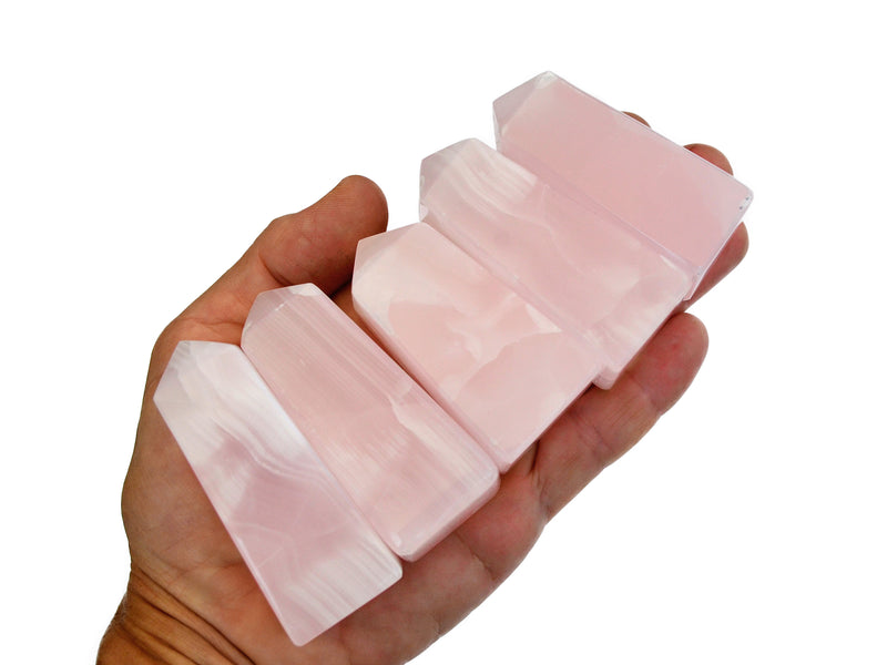 Five pink mangano calcite obelisks 65mm on hand with white background