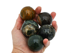 Five ocean jasper crystal spheres 40mm-45mm on hand with white background