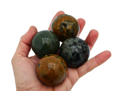 Four green, gray and mustard yellow ocean jasper spheres 40mm-45mm on hand with white background