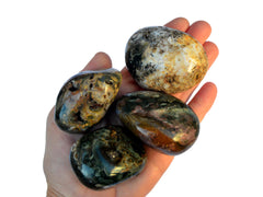 Four large ocean jasper tumbled stones  on hand with white background