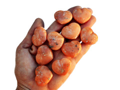 Ten orange calcite heart crystals 30mm on hand with white background