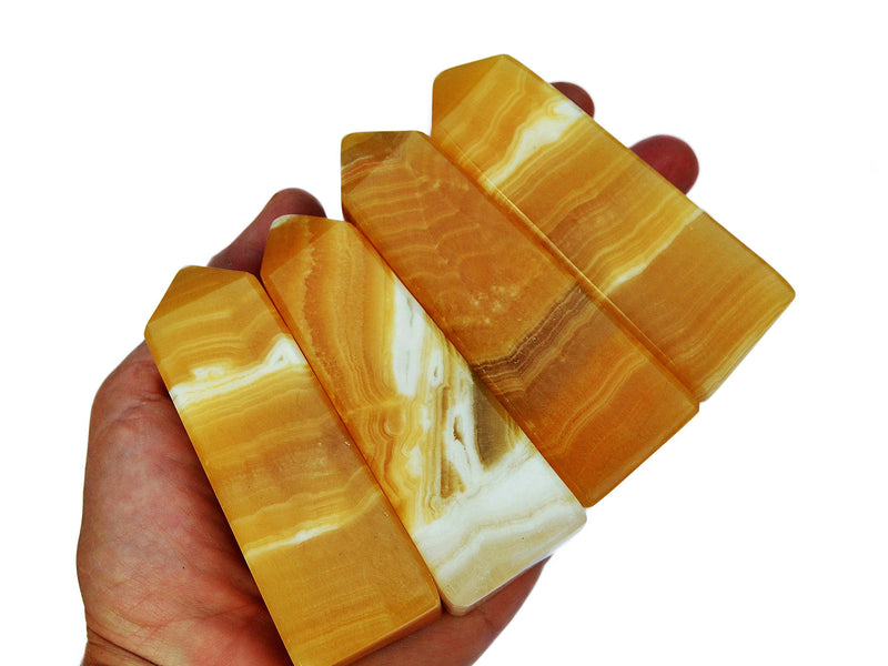 Four banded orange calcite towers 80mm-100mm on hand with white background