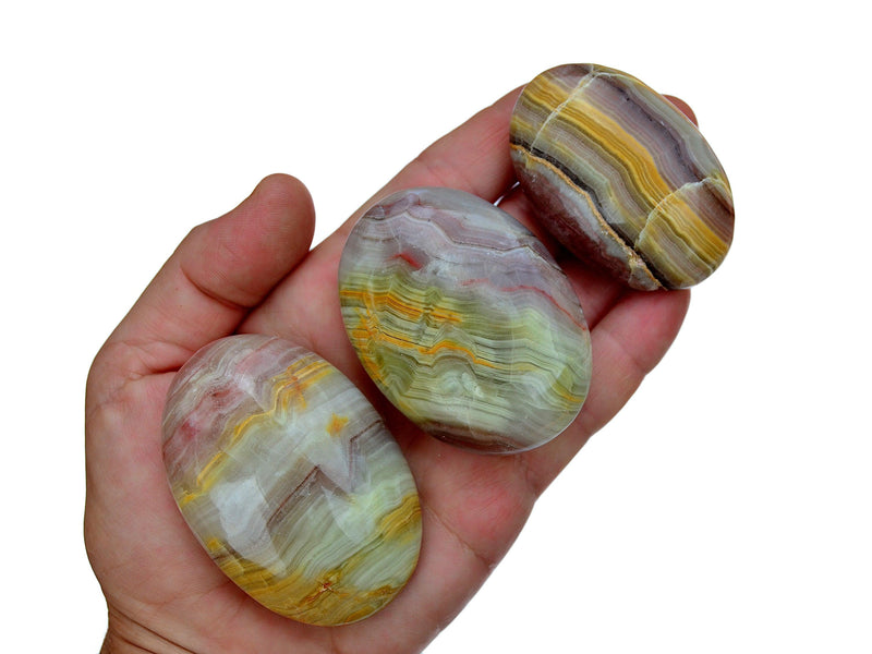 Three pink banded onyx palm stones 50mm-70mm on hand with white background