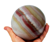 Extra large pink banded onyx sphere 110mm on hand with white background