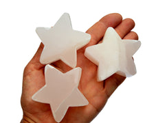 Three pink mangano calcite stars 60mm on hand with white background