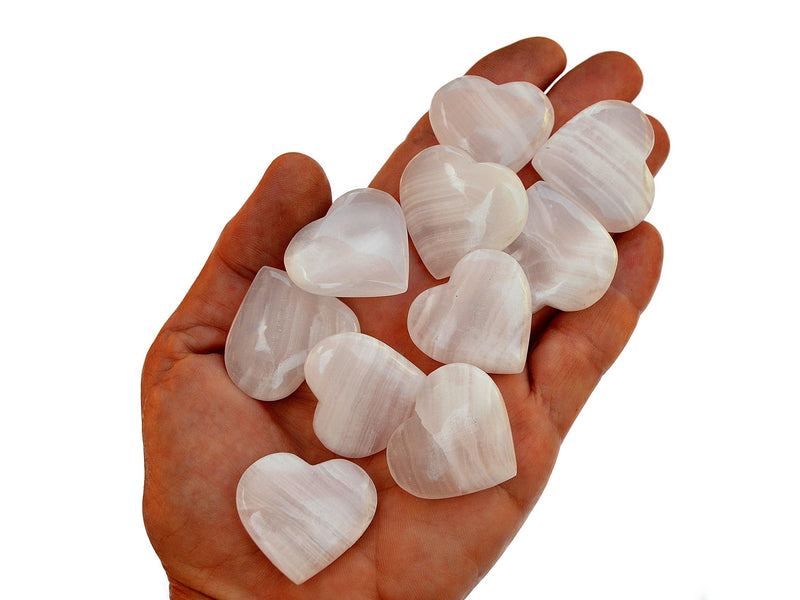 Ten pink mangano calcite crystal hearts 30mm-35mm on hand with white background 