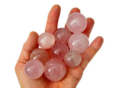 Some rose quartz crystal spheres 25mm-35mm on hand with white background