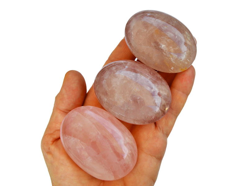 Three pink quartz palmstones 50mm on hand with white background