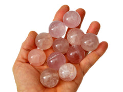 Several mini rose quartz crystal spheres 25mm on hand with white background