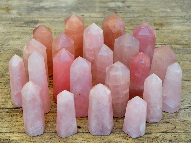 Several rose quartz faceted point crystals on wood table