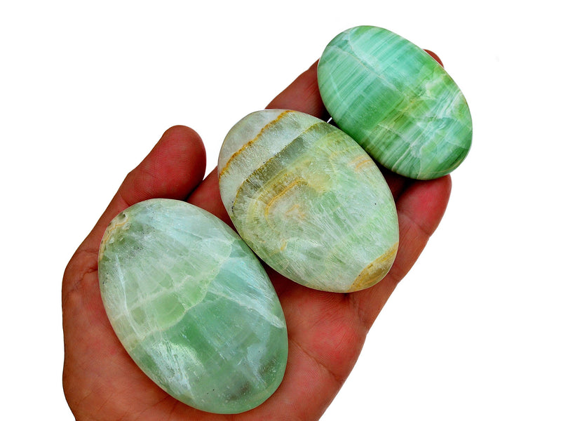 Three pistachio calcite palm stones 45mm-95mm on hand with white background