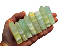Eight pistachio calcite faceted crystal points 50mm-55mm on hand with white background
