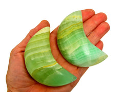 Two pistachio calcite moon crystals 70mm on hand with white background