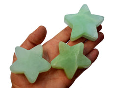 Three green pistachio calcite star shapped crystals 60mm on hand with white background