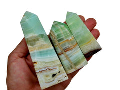 Three pistachio calcite crystal obelisks 55mm-125mm on hand with white background