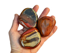 Three large polychrome jasper tumbled crystals on hand with white background