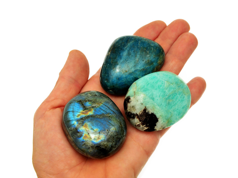 One large labradorite, blue apatite and green amazonite tumbled stones on hand with white background