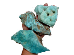 Three raw blue aragonite specimens on hand with white background