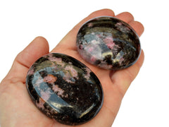 Two rhodonite palm stones 55mm- 60mm on hand with white background