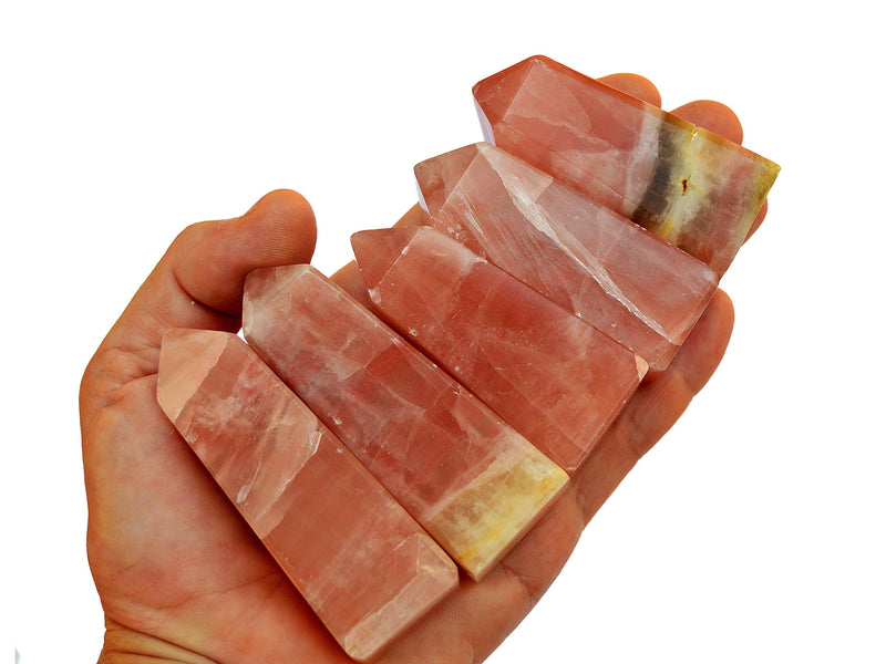 Five rose calcite crystal obelisks 55mm-85mm on hand with white background