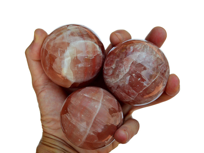 Three rose calcite spheres 55mm-60mm on hand with white background