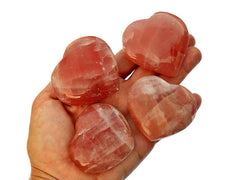 Four rose calcite heart crystals 45mm-70mm on hand with white background