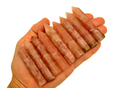 Nine rose calcite faceted crystal points 70mm on hand with white background