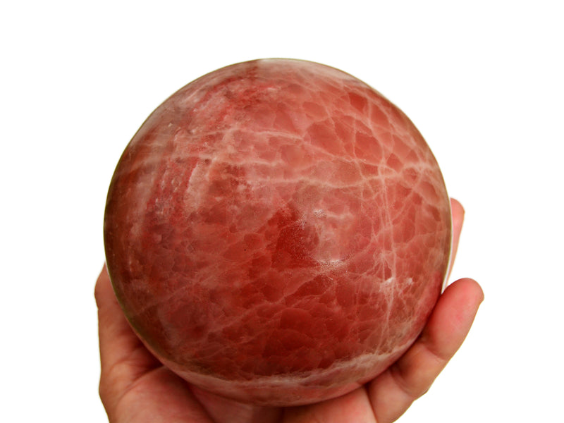 Large rose calcite sphere 100mm on hand with white background