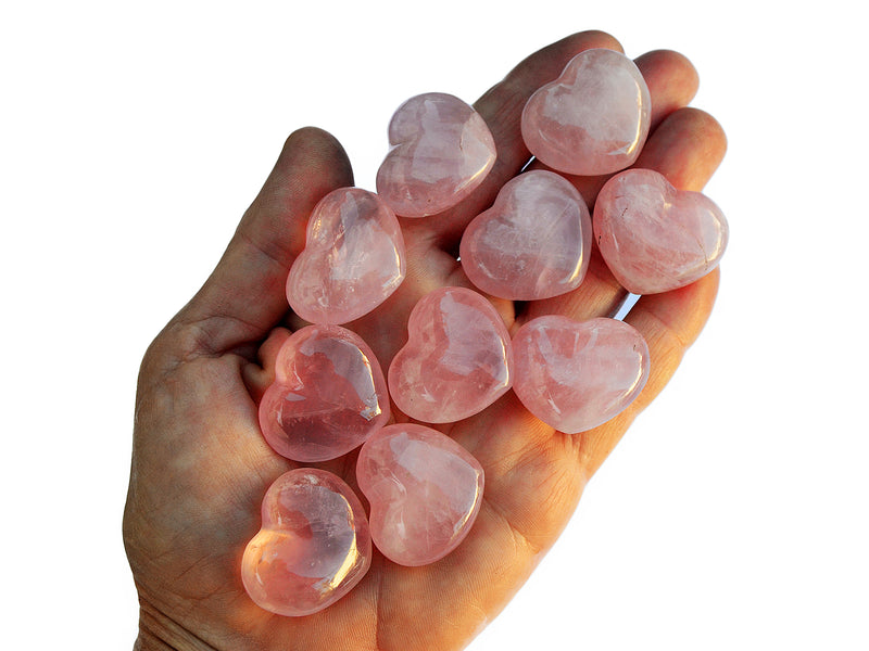 Ten rose quartz puffy heart crystals 30mm on hand with white background