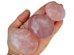 Three pink quartz palm stones 70mm-40mm on hand with white background