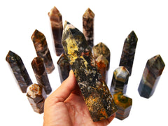 One sea jasper obelisk 140mm on hand with background with some towers on white