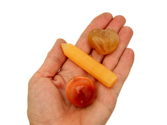 Small carnelian sphere, orange calcite point and yellow hematoid quartz heart on hand with white background