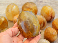 One golden healer quartz free form on hand with background with some crystals on wood table