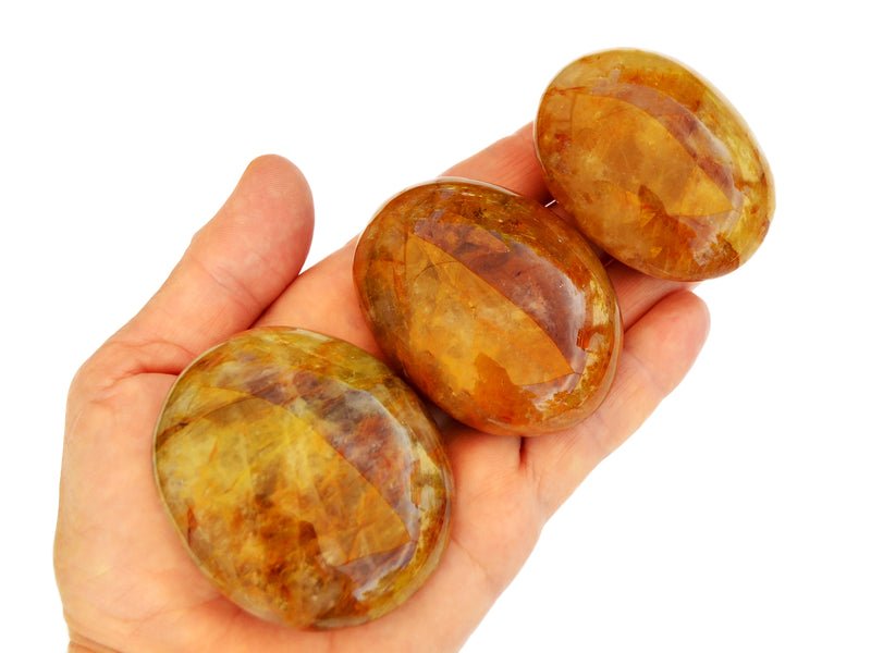 Three yellow hematoid quartz palm stones 50mm-65mm on hand with white background