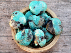 Several large green amazonite crystal hearts inside a bowl